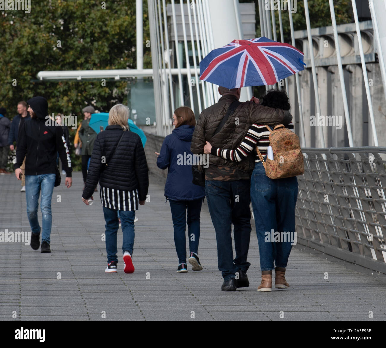 London, UK. 7th Oct 2019. UK Weather: A couple with a Union Flag umbrella walk along Jubilee bridge on a dull and wet day. Celia McMahon/Alamy Live News. Credit: Celia McMahon/Alamy Live News Stock Photo