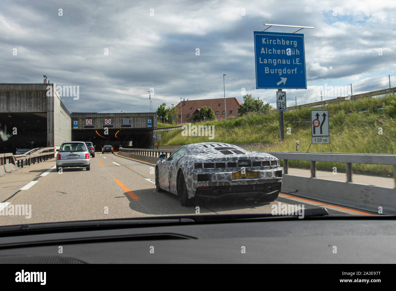 A McLaren GT prototype test vehiche photographed doing road tests in Switzerland. Rear end and air intake heavily camouflaged with both camo tape and extra panels. Tail lights are hidden under mesh panel. The new GT model was first announced at the 2019 Geneva Auto Salon, but details about the car was first released in May same year. These images were taken in June 2019 and differs from earlier photos in having extra panels popped onto the rear and the side, as well as tail lights camouflaged. The outline of the tail lights are visible through the tape. Stock Photo