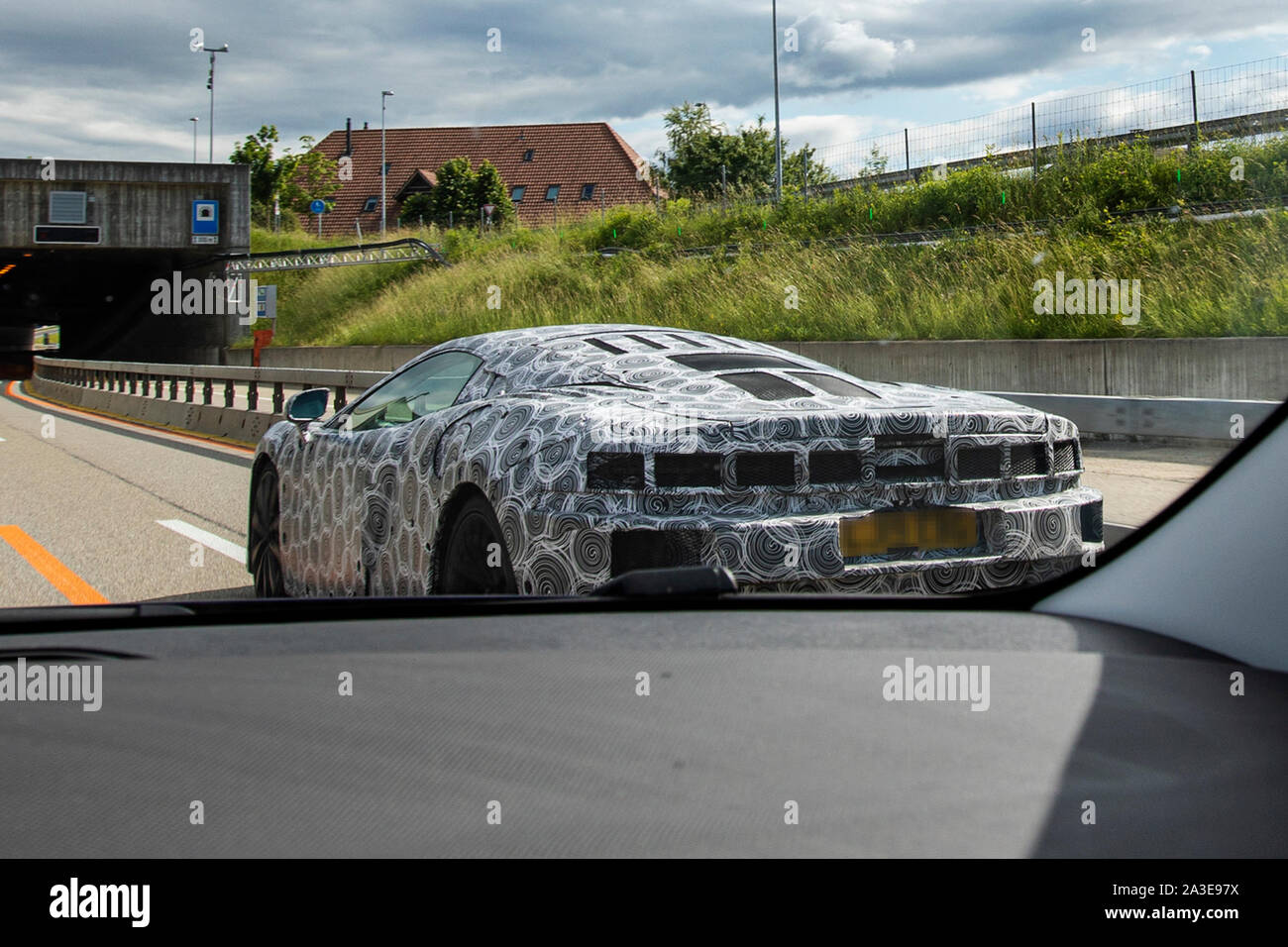 A McLaren GT prototype test vehiche photographed doing road tests in Switzerland. Rear end and air intake heavily camouflaged with both camo tape and extra panels. Tail lights are hidden under mesh panel. The new GT model was first announced at the 2019 Geneva Auto Salon, but details about the car was first released in May same year. These images were taken in June 2019 and differs from earlier photos in having extra panels popped onto the rear and the side, as well as tail lights camouflaged. The outline of the tail lights are visible through the tape. Stock Photo