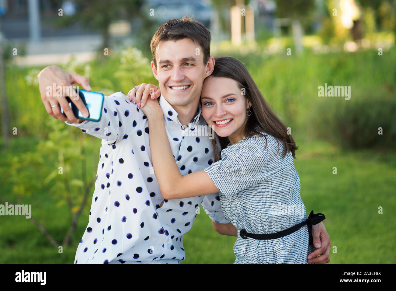 Beautiful couple in love dating outdoors and smiling. Girl persuades her boyfriend to take a picture of herself together. Selfie. Keep a moment in min Stock Photo