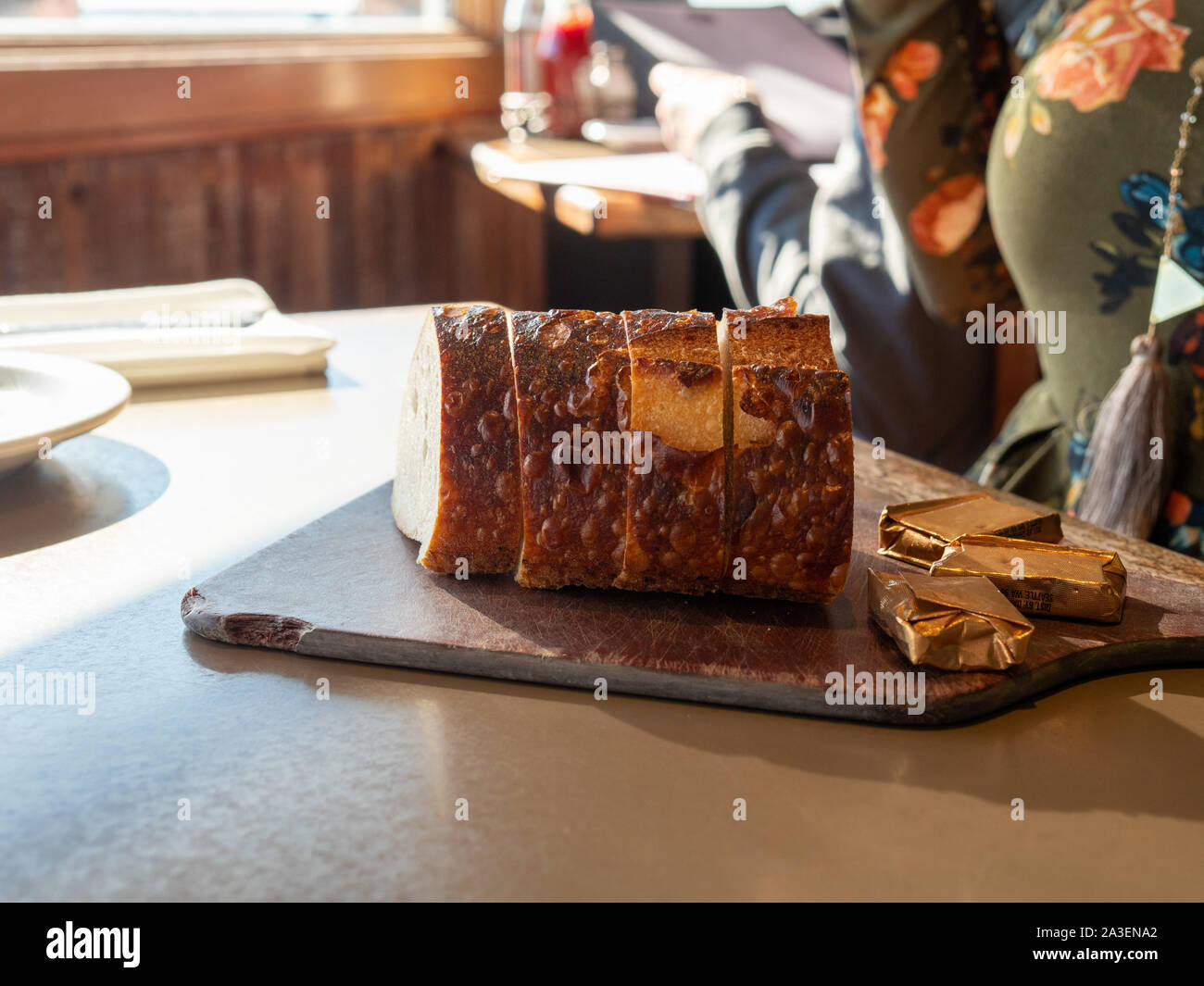 Bread and sticks of butter with carbs on a serving board at restaurant Stock Photo