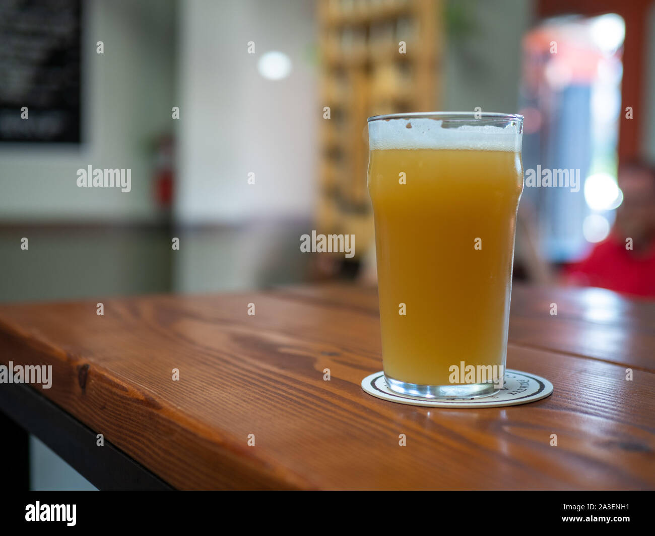 Full freshly poured glass of beer with foam on head on restaurant table