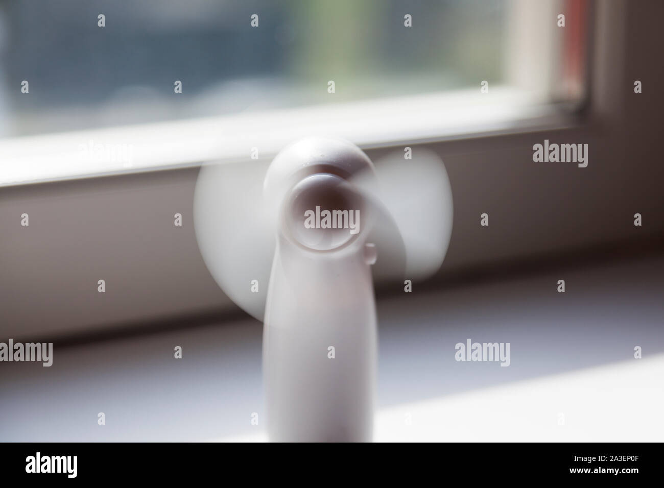 a small white table fan that stands in the windowsill when it is warm outside and indoors Stock Photo