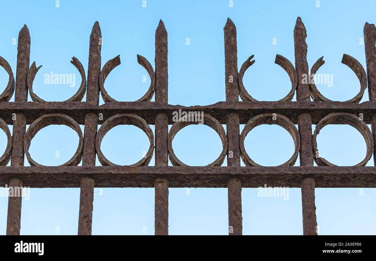 closeup detail of an antique rusting wrought iron fence at the old train station in Tel Aviv Israel with a clear blue sky background Stock Photo