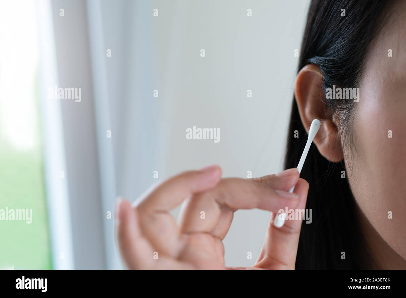 woman cleaning the ear with a cotton swab. Healthcare and ear cleaning