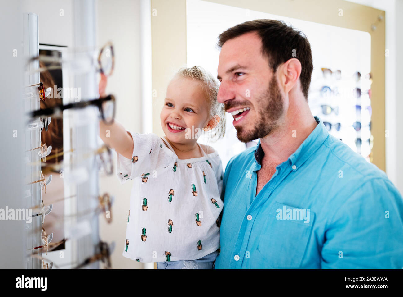 Health care, eyesight and vision concept. Little girl choosing glasses