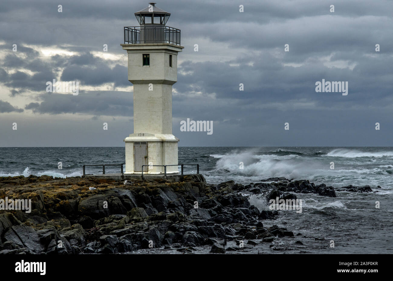 Akranes Lighthouse right on the coast with a high wind making waves, west Iceland Stock Photo