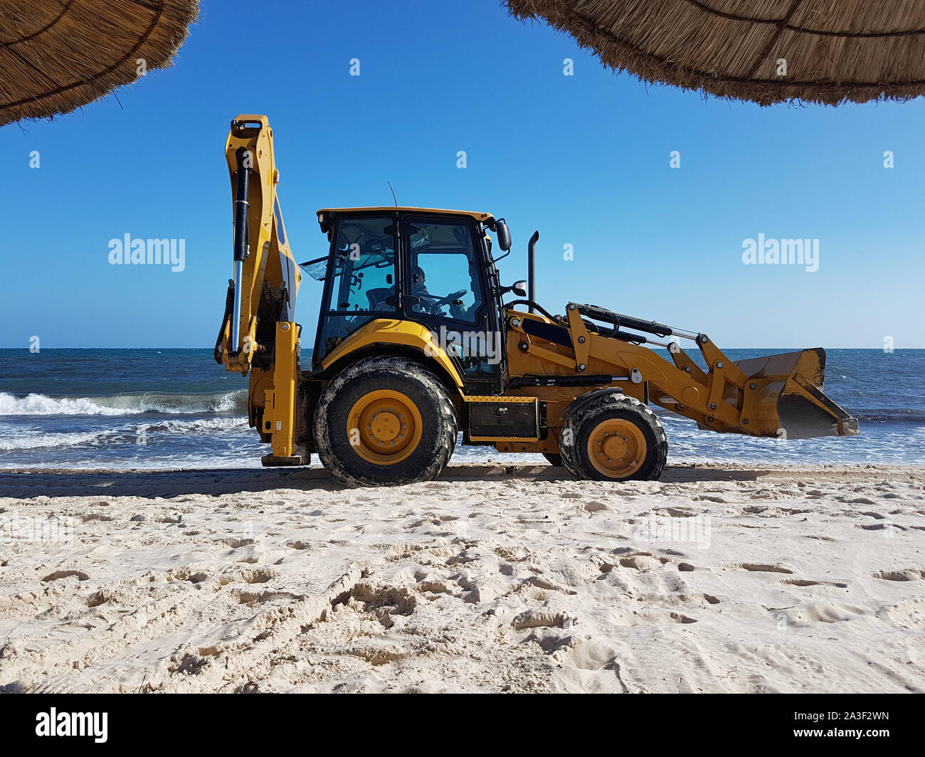 Yellow digger in the empty clean beach Stock Photo - Alamy