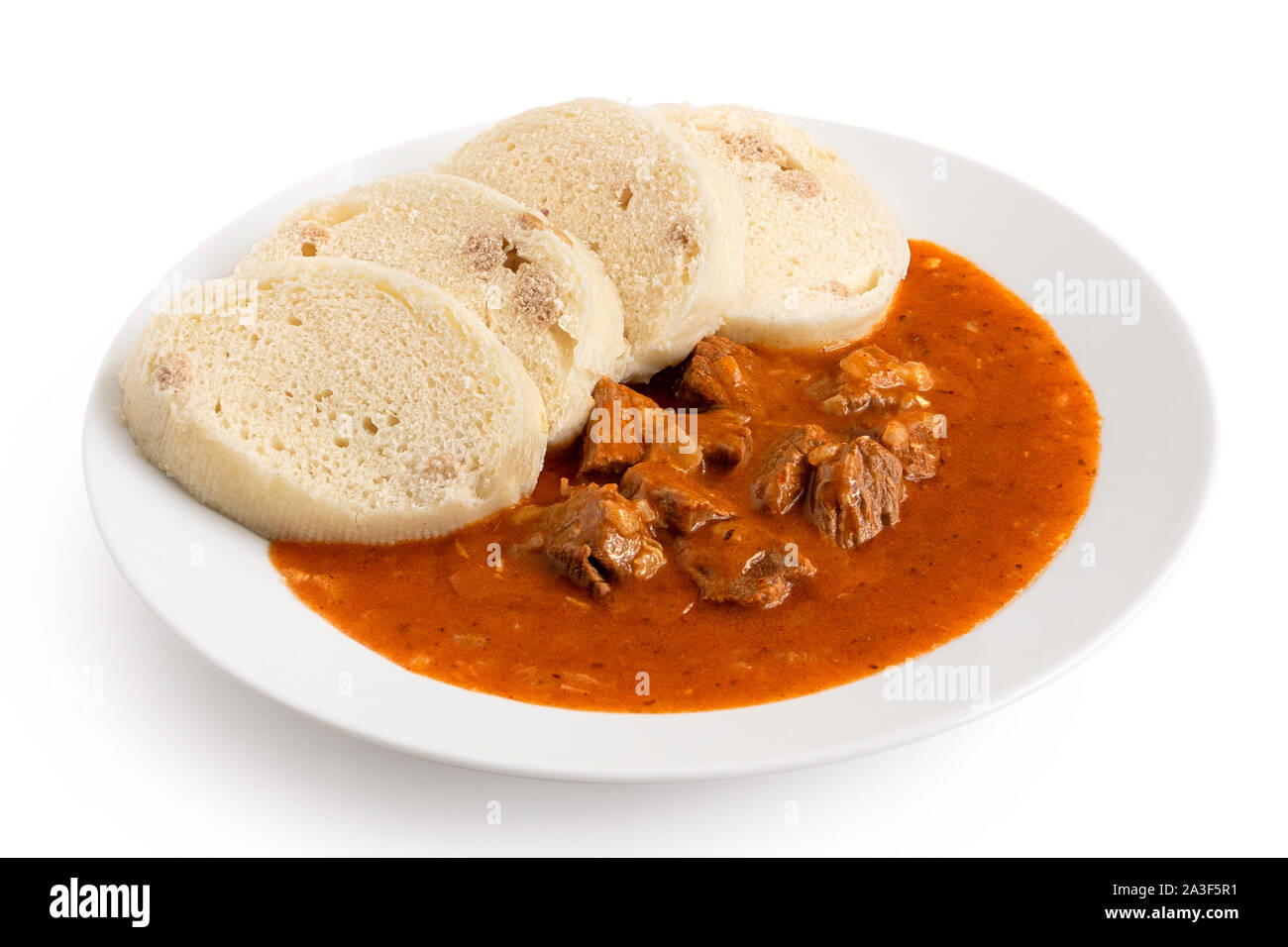 Beef goulash with bread dumplings on white ceramic plate isolated on
