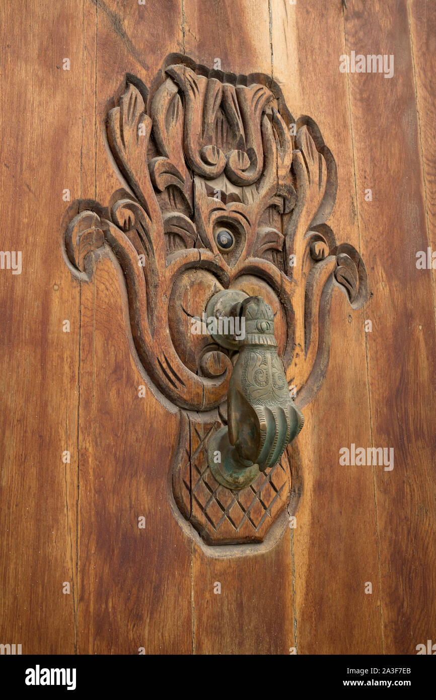 Old knocker in the shape of a hand on a wooden door in Asilah, Morocco Stock Photo