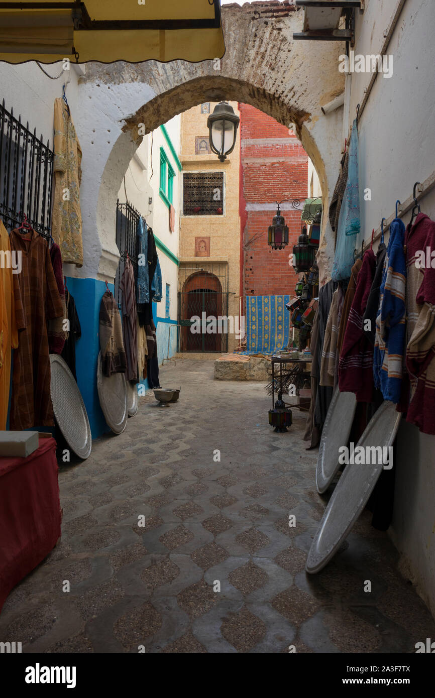 Narrow old street  with merchandise in the medina of Asilah, Morocco Stock Photo