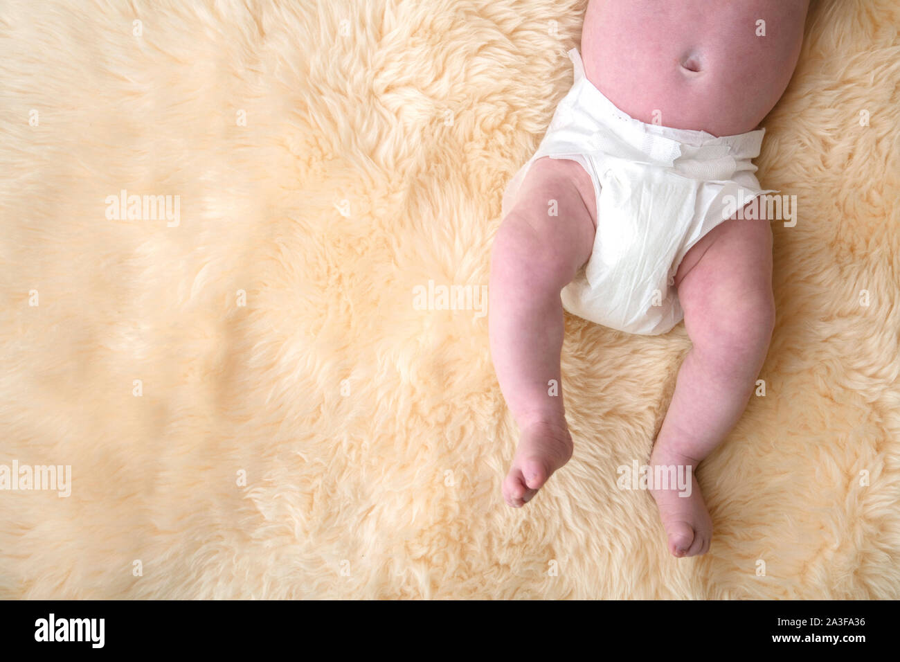Newborn Baby Legs With White Nappy Diaper On A Fur Background Stock