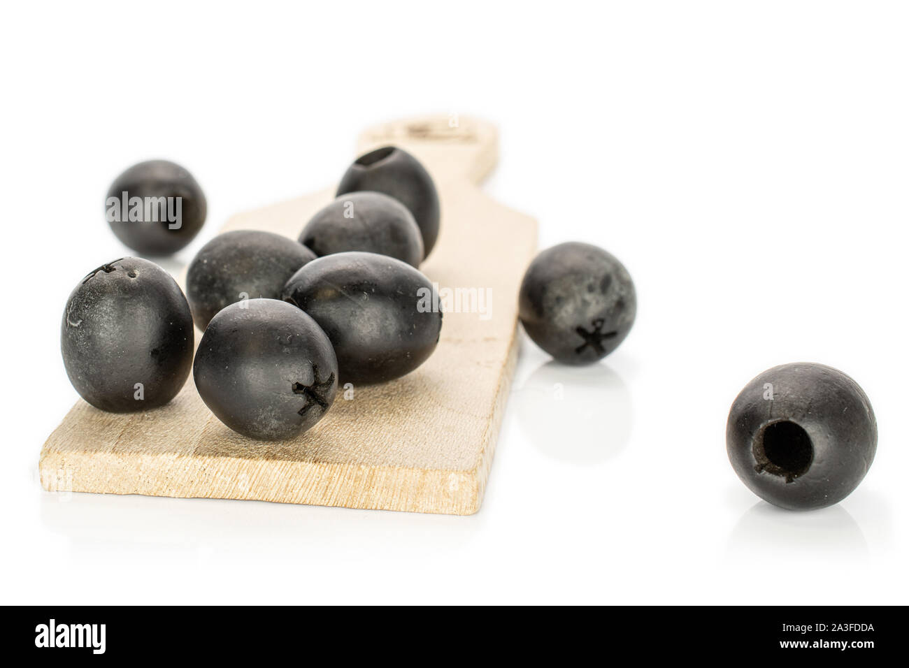 Lot of whole disordered tasty black olive on wooden board isolated on white background Stock Photo
