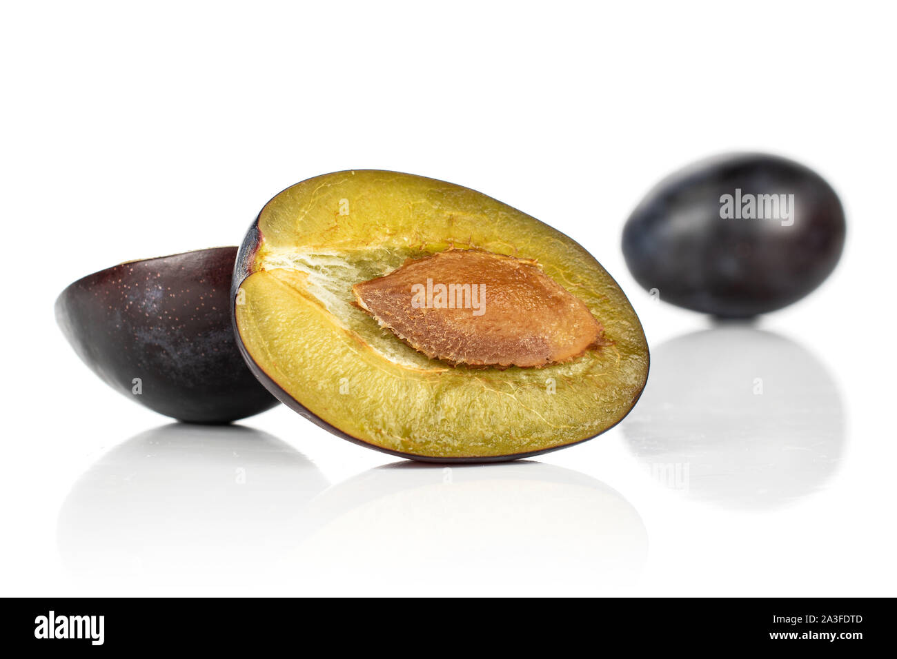 Group of one whole two halves of fresh purple plum front focus isolated ...