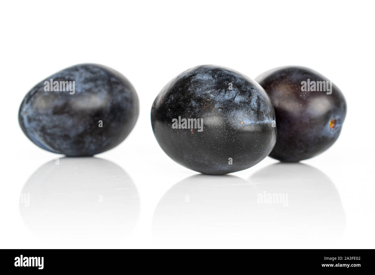 Group of three whole fresh purple plum front focus isolated on white ...