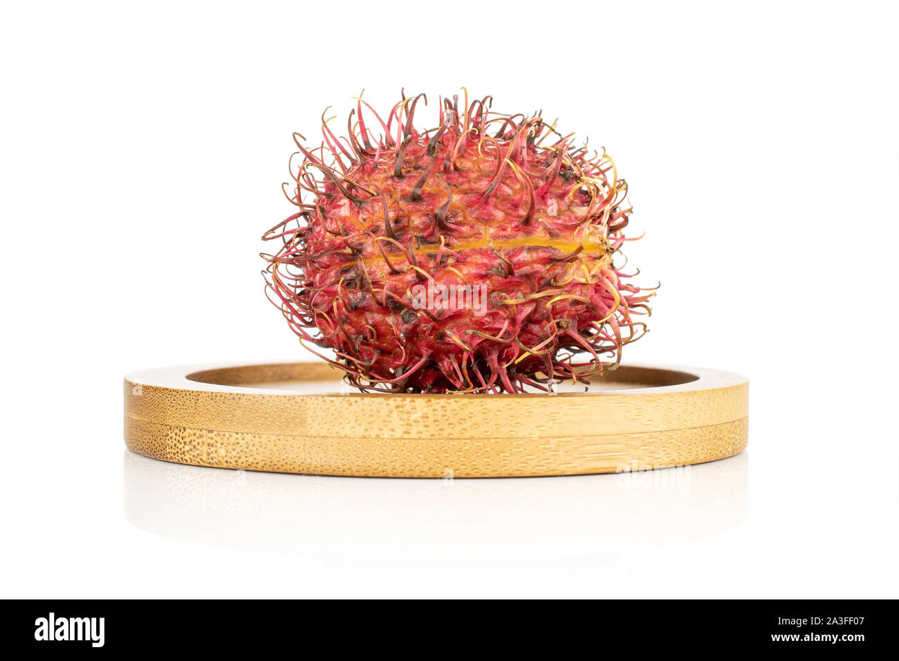 One whole fresh red rambutan on bamboo plate isolated on white ...
