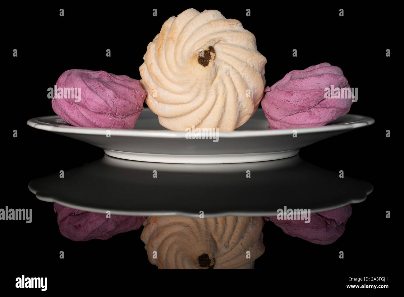 Group of three whole fresh pastel zefir on white plate isolated on black glass Stock Photo