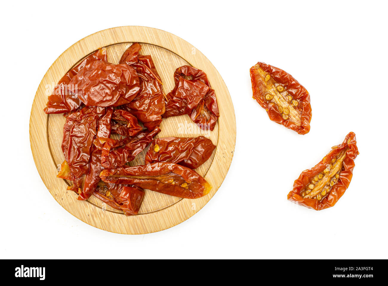 Lot of slices of dry red cherry tomato on bamboo plate flatlay isolated on white background Stock Photo