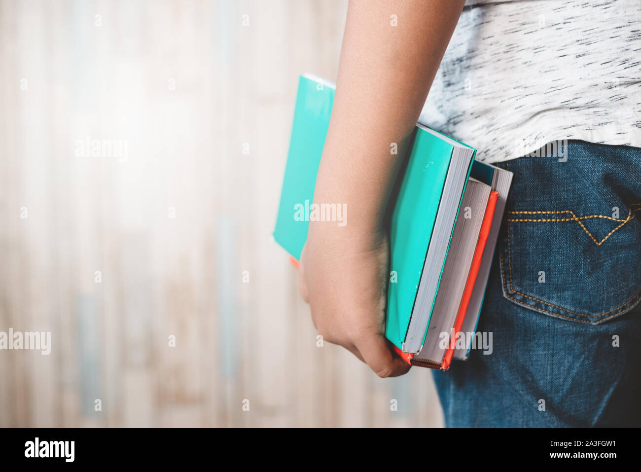tight shot of teenage midsection holding a colorful books. concept of education, student and lifestyle Stock Photo