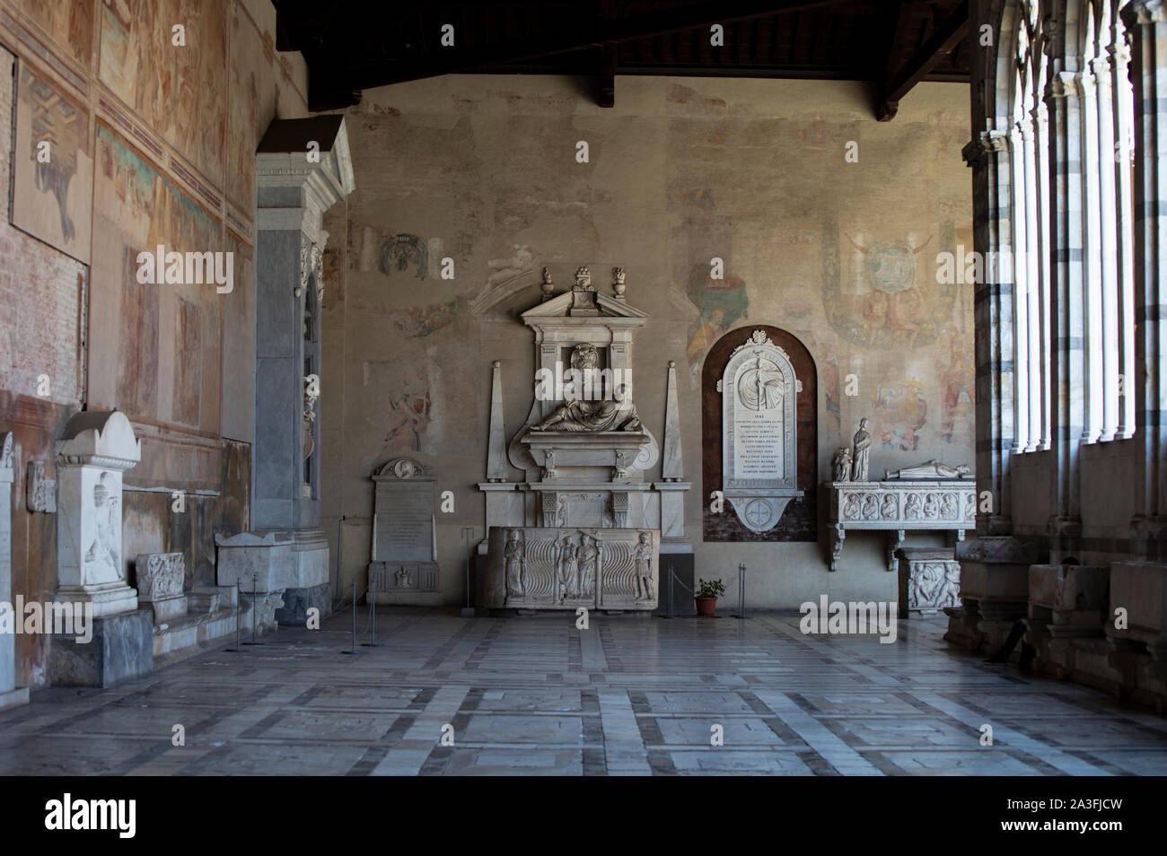 Detail of the interior marble arcades & gothic arches of the Camposanto on the Campo Dei Miracoli in Pisa, showing the ancient tombs and frescos. Stock Photo