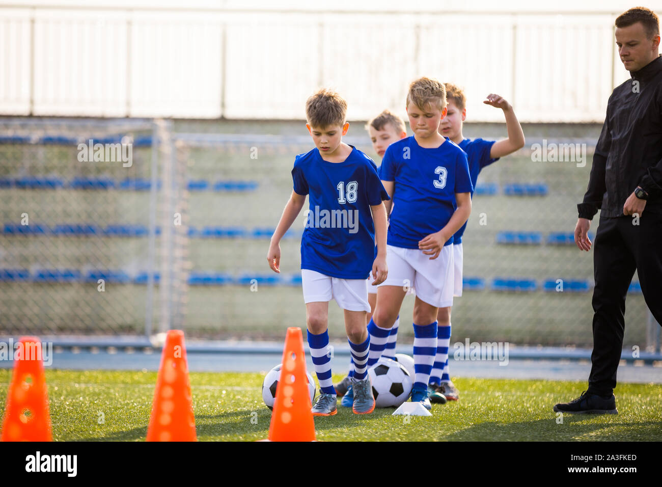 Boys Training Football on Pitch Witch Youth Coach. Group of Young School  Age Boys On Training Session With Youth Coach. Kids in Blue Jersey Schools  Stock Photo - Alamy