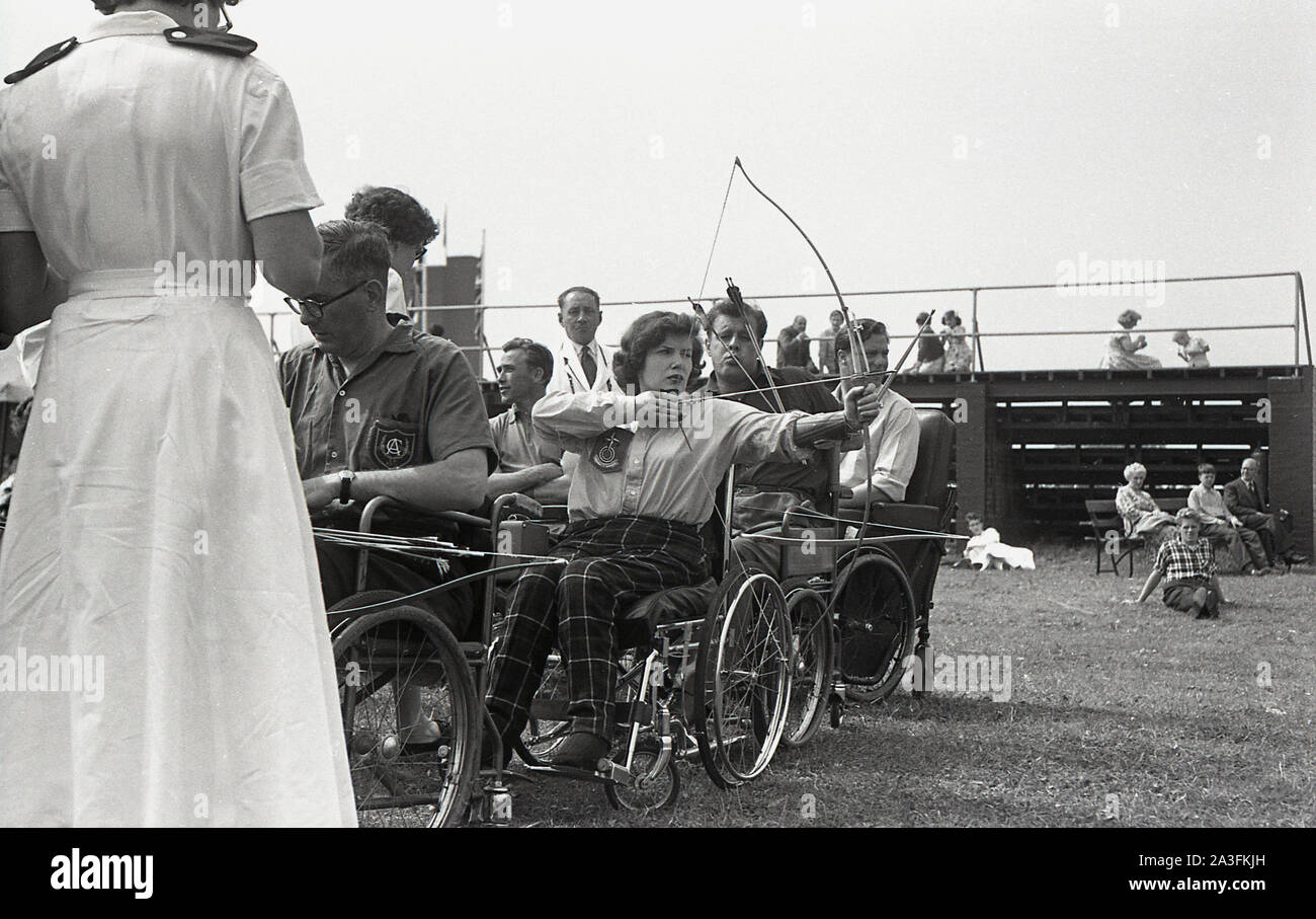1950s, historical, Stoke Mandeville games, adult competitors in wheelchairs taking part in the archery competition. The games at the hospital had been established by Dr Guttmann in 1948 involving WW2 veterans with spinal injuries and are considered the first Paralympic Games. Stock Photo