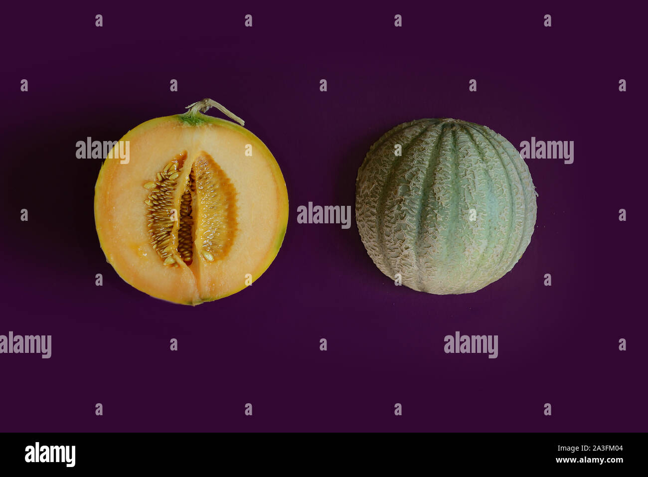 Two halves of cantaloupe melon on purple background Stock Photo