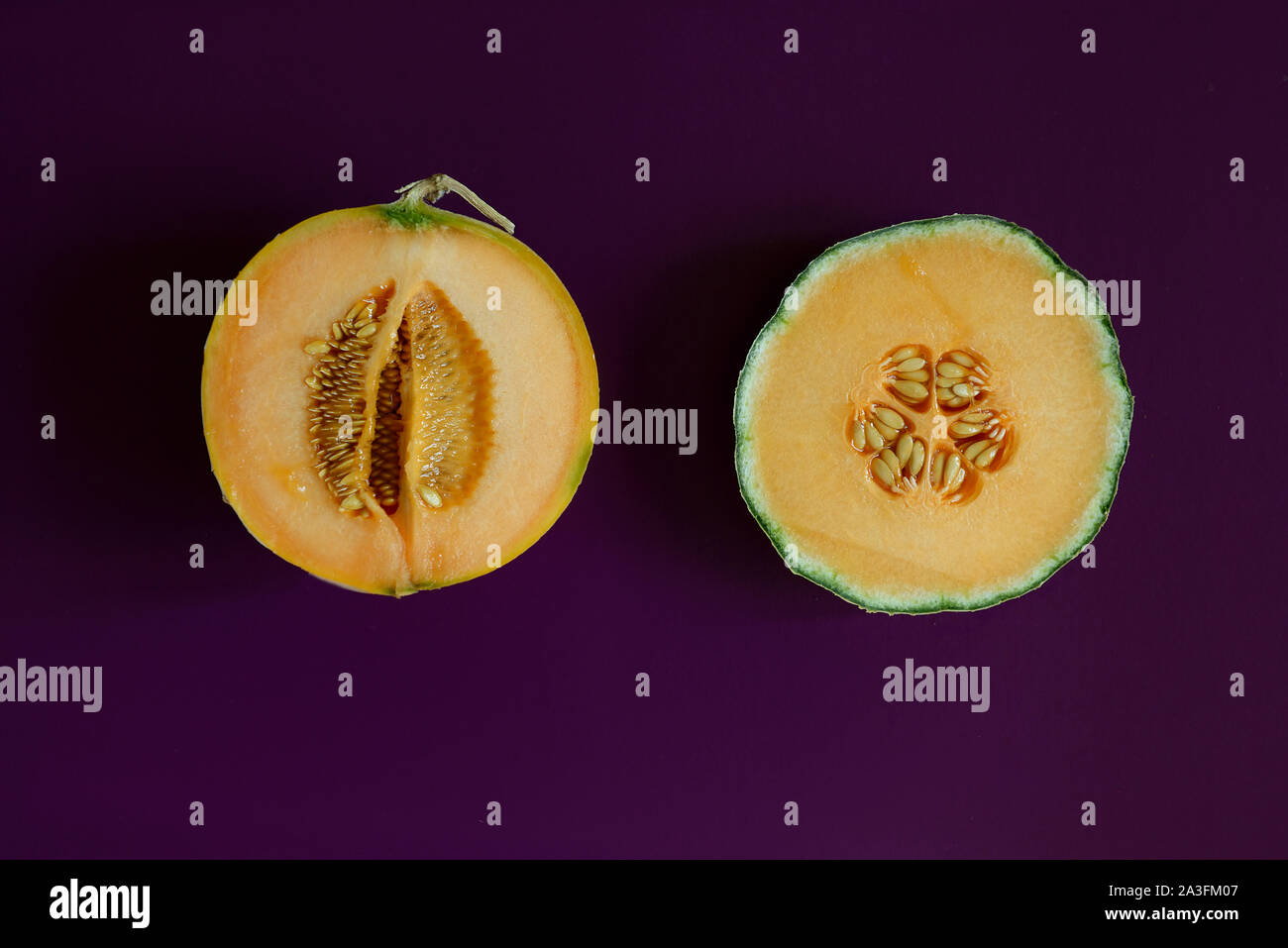 Two halves of cantaloupe melon on purple background Stock Photo