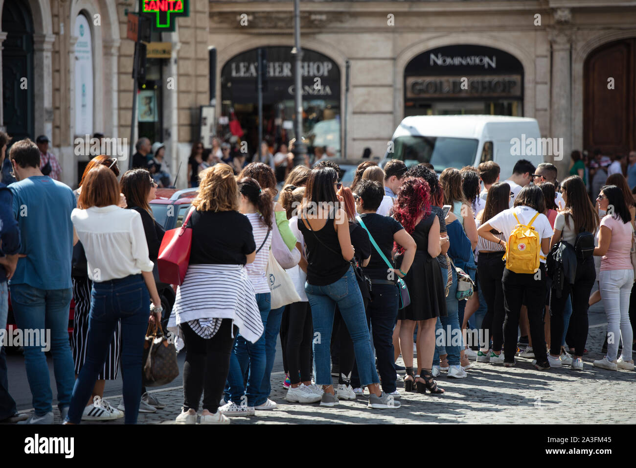 People in a queue on a street on a sunny day in Italy. Stock Photo