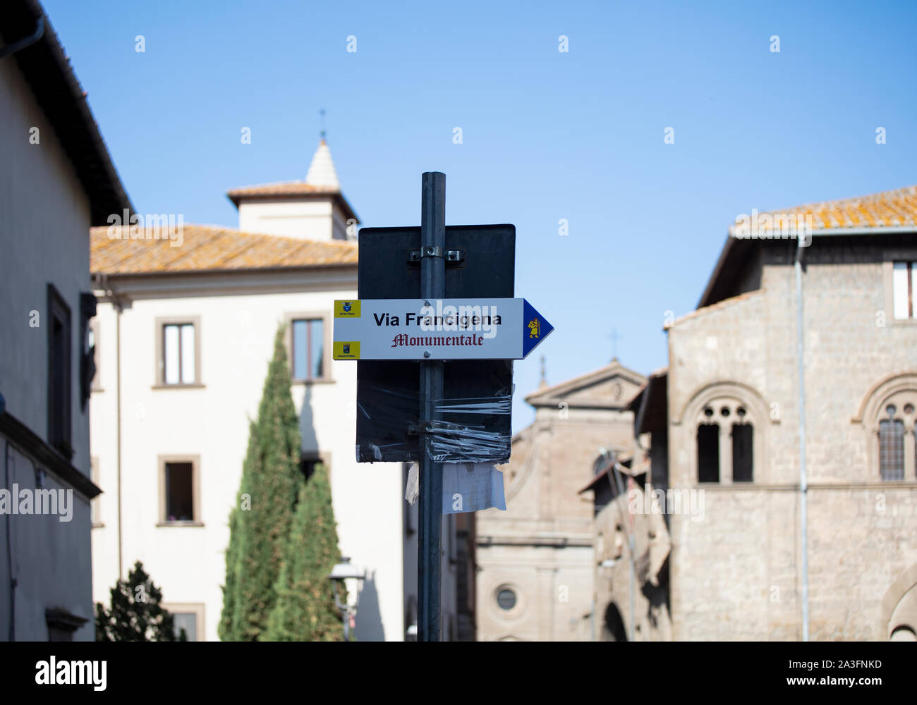 Road sign for the Via Francigena, an ancient pilgrimage walk between Canterbury and  Rome. In the background the cathedral in Viterbo can be seen. Stock Photo