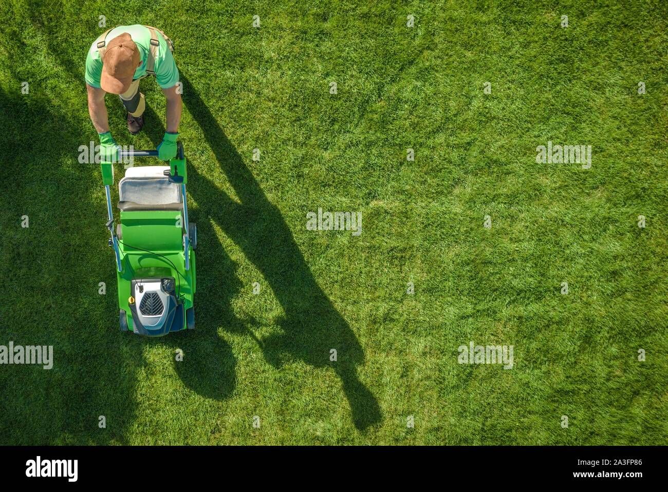 Lawn Moving Aerial Photo. Caucasian Gardener with Gasoline Grass Mower at Work. Landscaping Business. Industrial Theme. Stock Photo