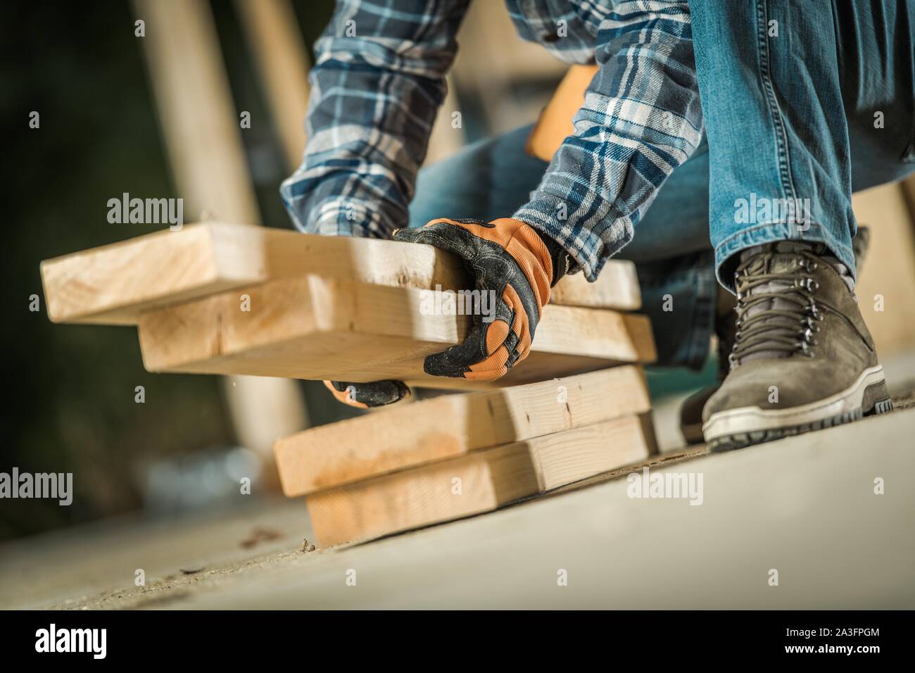 Carpenter Contractor Worker Taking Wood Building Elements From a Floor. Industrial Concept. Stock Photo