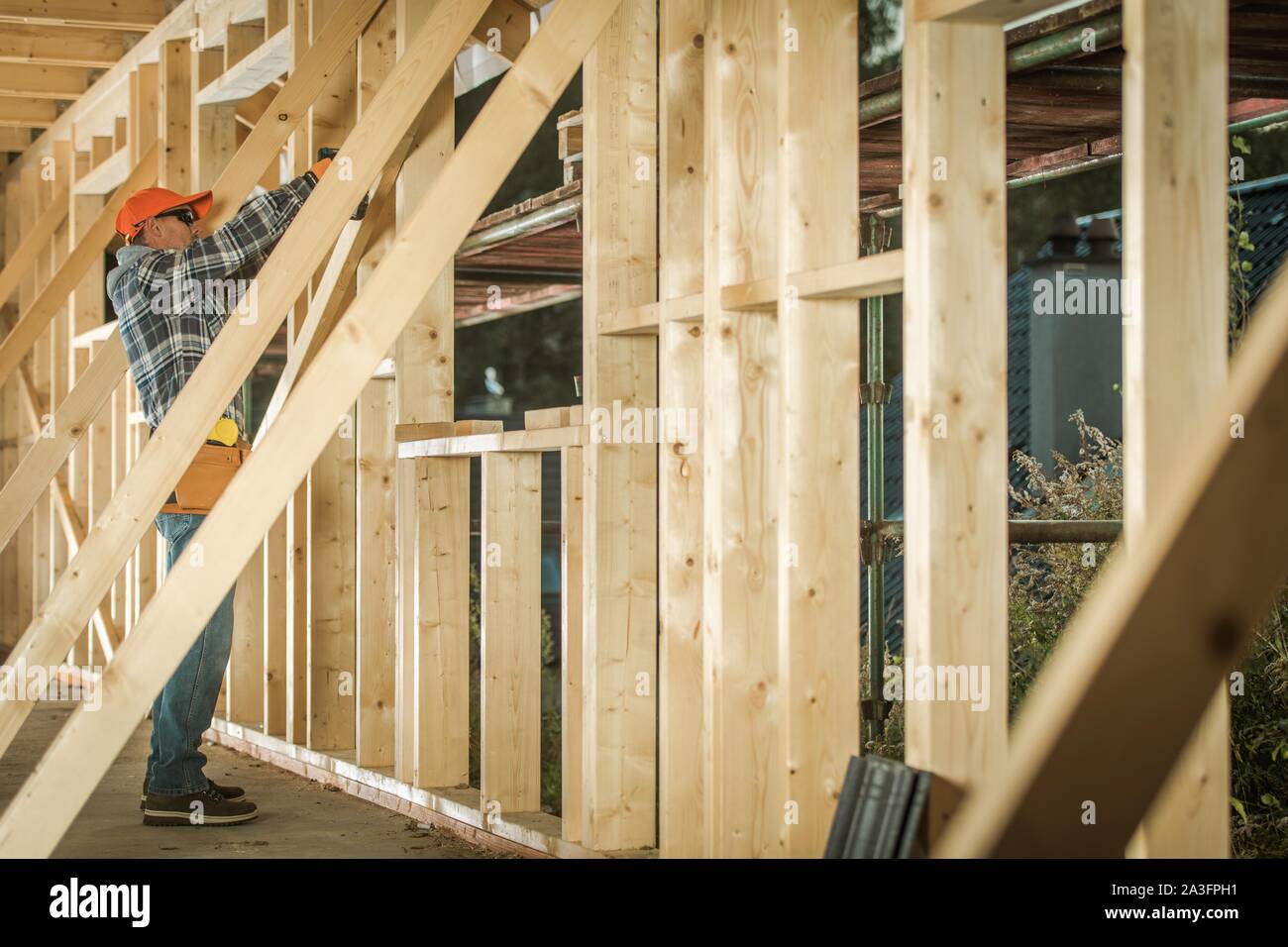 Wooden House Construction Job. Caucasian Contractor Carpenter Finishing Building wood Beams Frame. Industrial Theme. Stock Photo