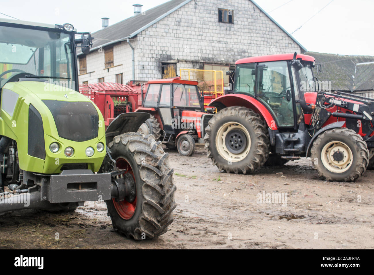 Red and green tractors and agricultural equipment in the yard of a