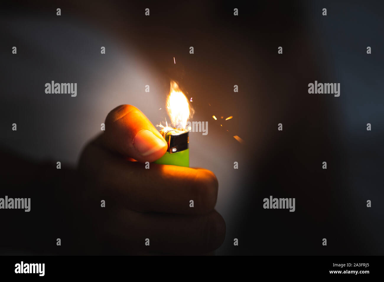 close up of a hand holding a lighter in the dark and starting fire