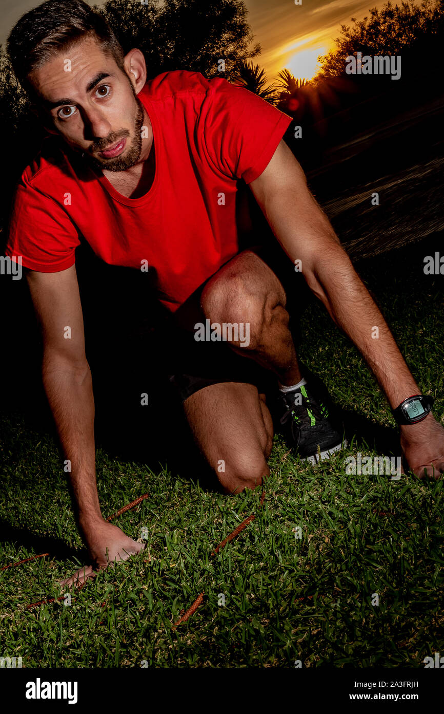 athlete placed in the starting position of a race on green grass Stock Photo