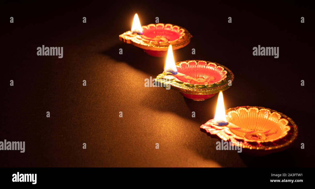 Diwali, Hindu festival of lights. Clay diyas candles illuminated in Dipavali. Oil lamps on traditional tray, copy space Stock Photo