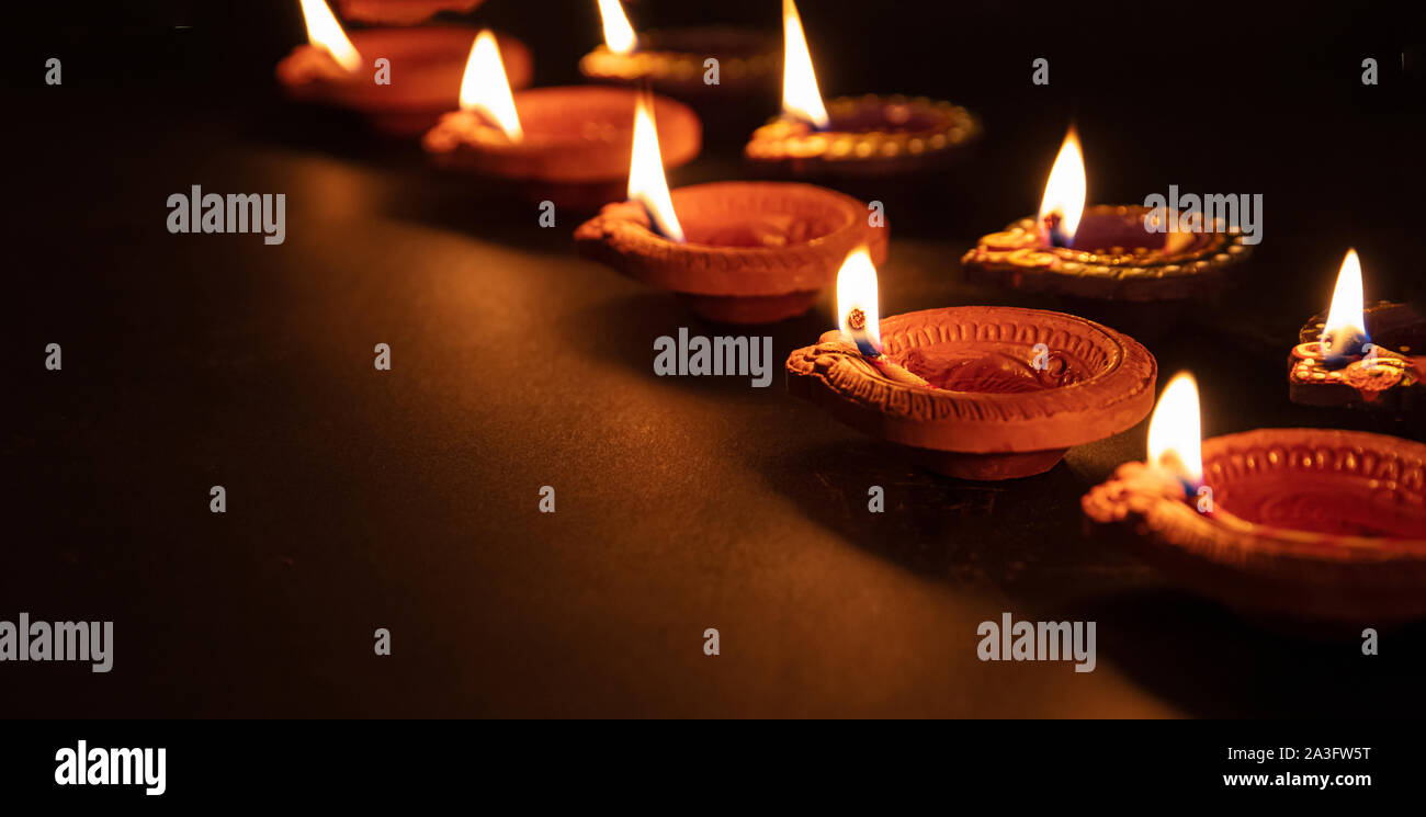 Happy Diwali. Clay diya candles illuminated in Dipavali, Hindu festival of  lights. Traditional oil lamps on dark background, banner, copy space Stock  Photo - Alamy