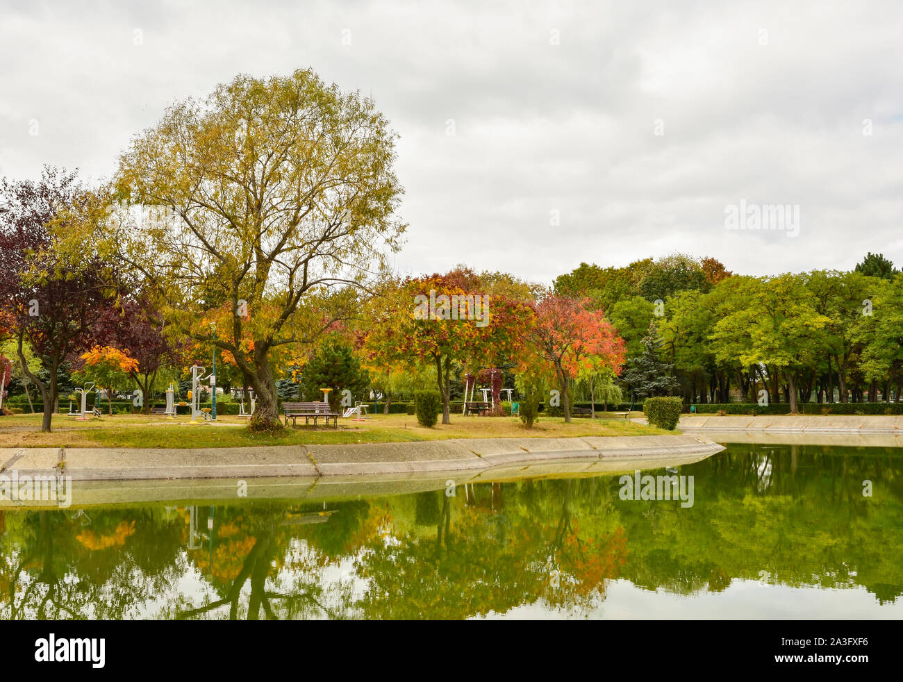 Outdoors autumn landscape, trees on a small island on a lake of a recreational park in Ploiesti City , Romania Stock Photo