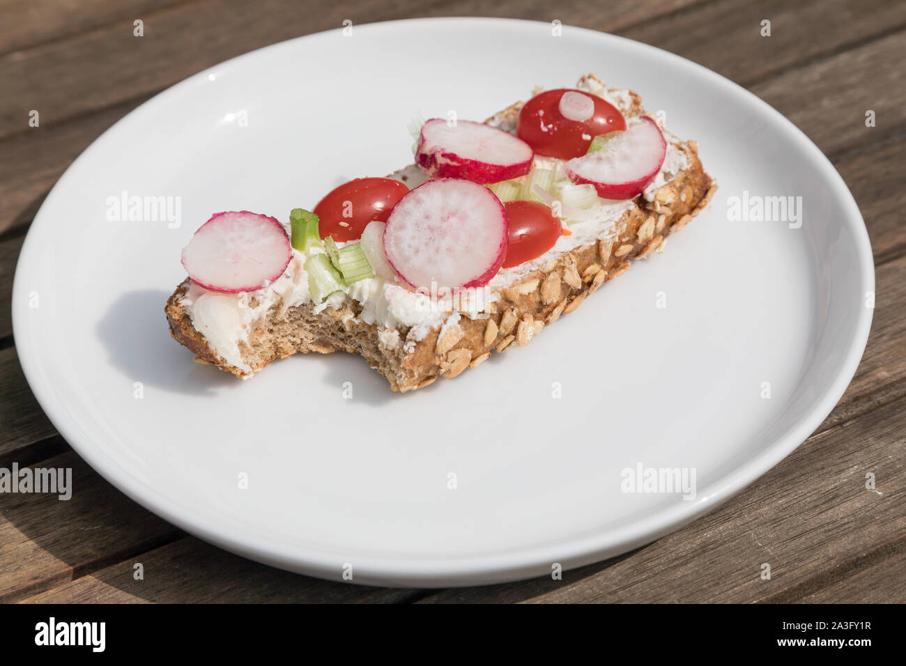 bitten grains bun with vegetables Stock Photo