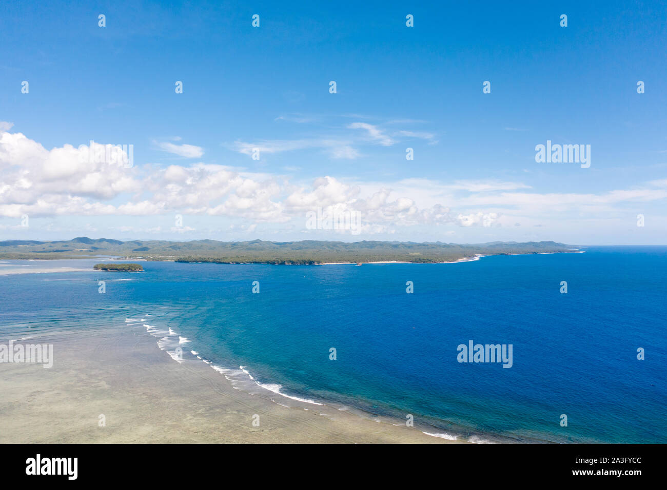 Seascape, coast of the island of Siargao, Philippines. Blue sea with waves and sky with big clouds, top view. Stock Photo