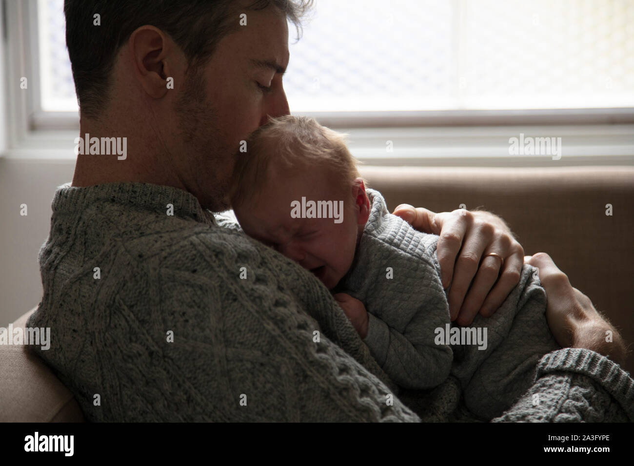 Father comforting a crying upset baby. Fatherhood, parenting concept Stock Photo