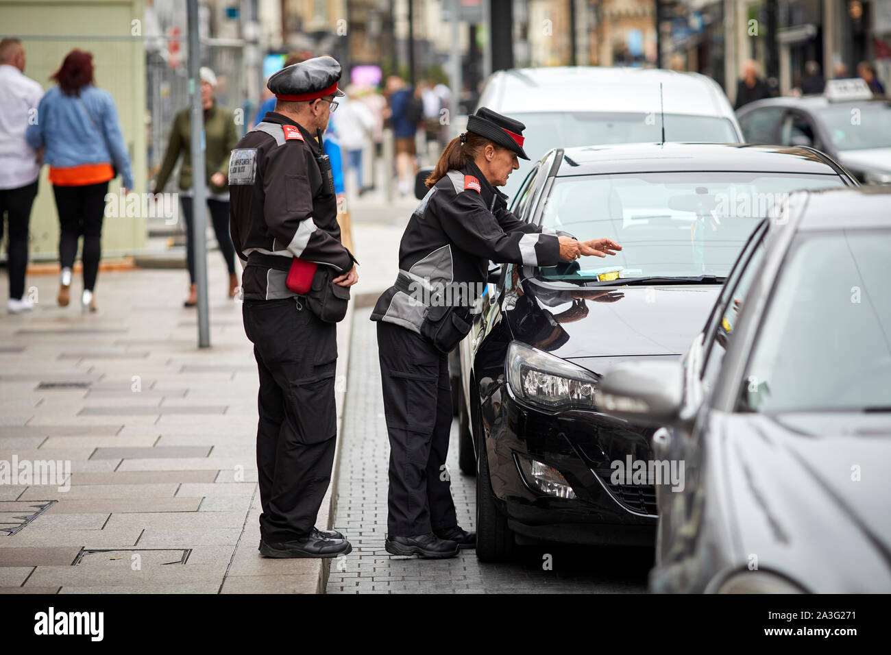 Cardiff Wales, on High Street council public servant traffic wardens giving a ticket Stock Photo