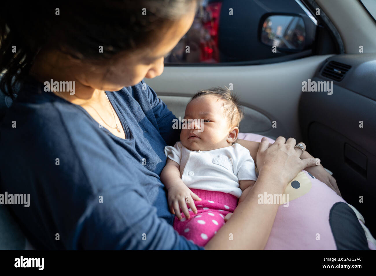 portrait of infant baby laying on mother's lap while in the car Stock Photo