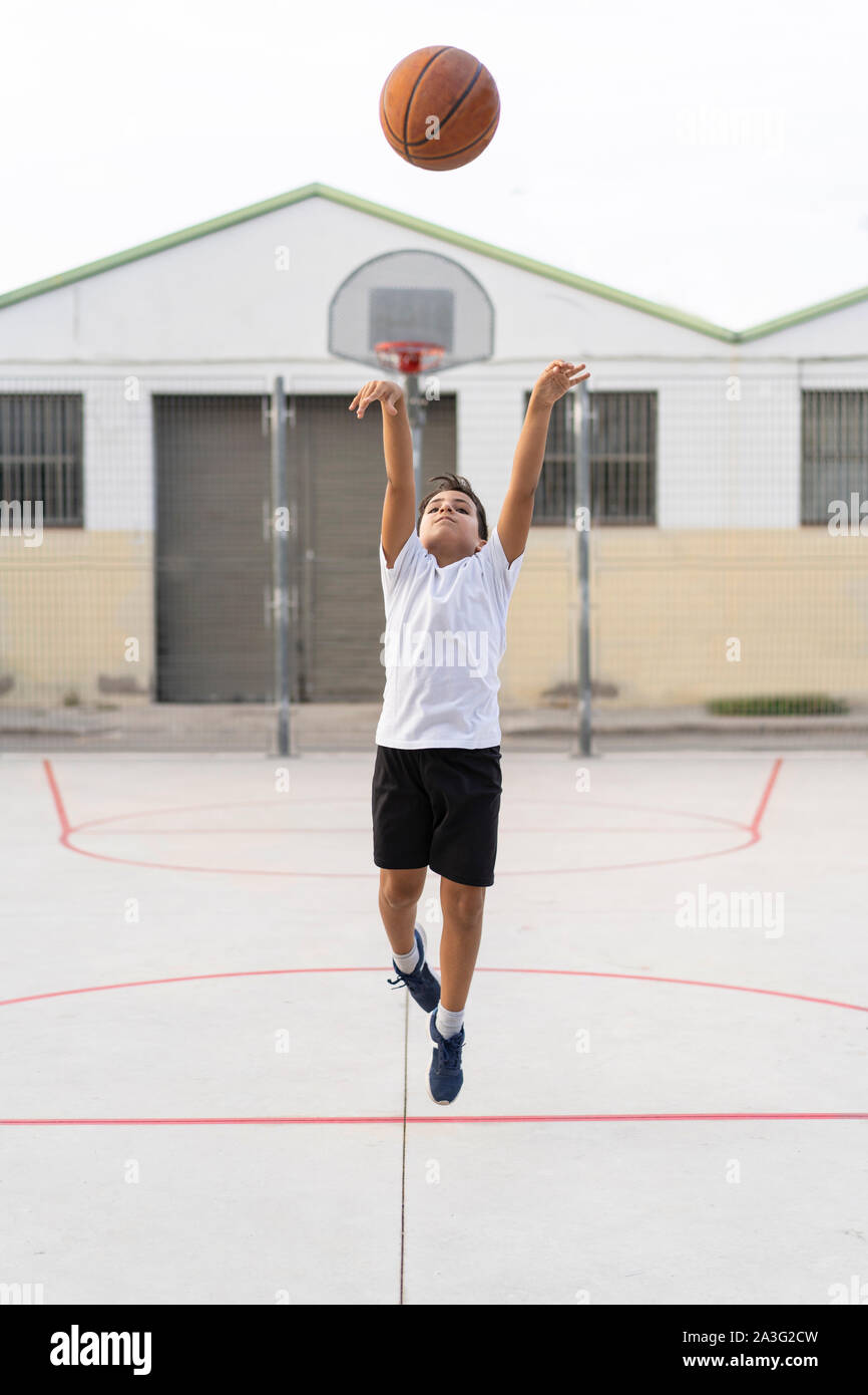 Kid playing basketball alone  in a street court Stock Photo
