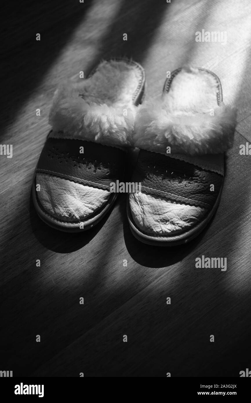 Women's slippers with a sheepskin on a wooden floor. BW Stock Photo