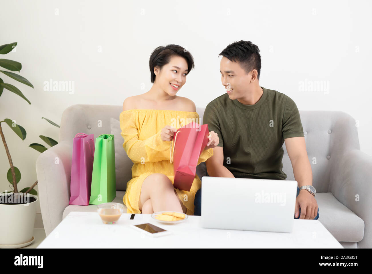 Young Asian couple in sofe websurfing and shpping on internet Stock Photo