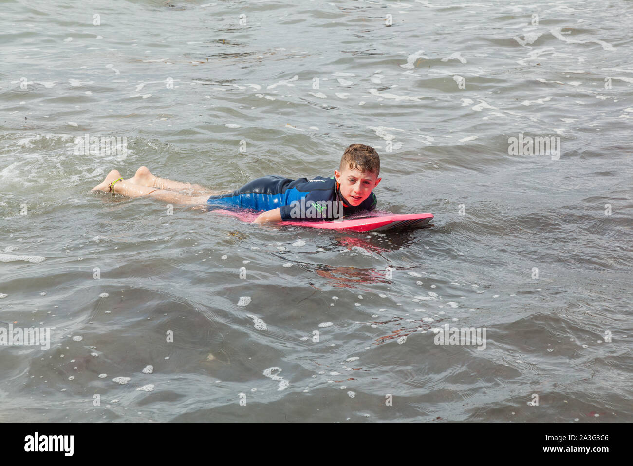 Ten year old boy surfing at Outer Hope Cove, Mouthwell sands beach