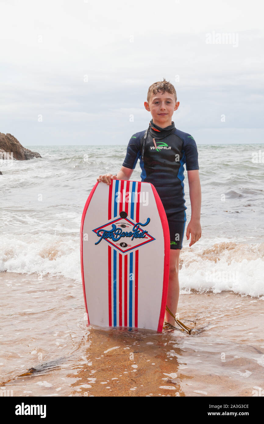 Ten year old boy surfing at Outer Hope Cove, Mouthwell sands beach, Kingsbridge, Devon, England, United Kingdom. Stock Photo