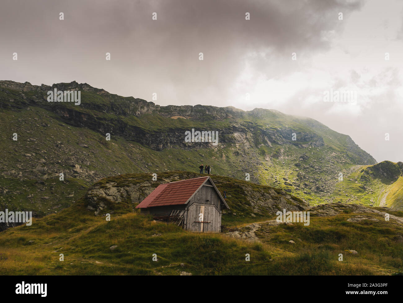 Scenic view of old,small cottage and tourists in Fagaras mountains, Romania Stock Photo
